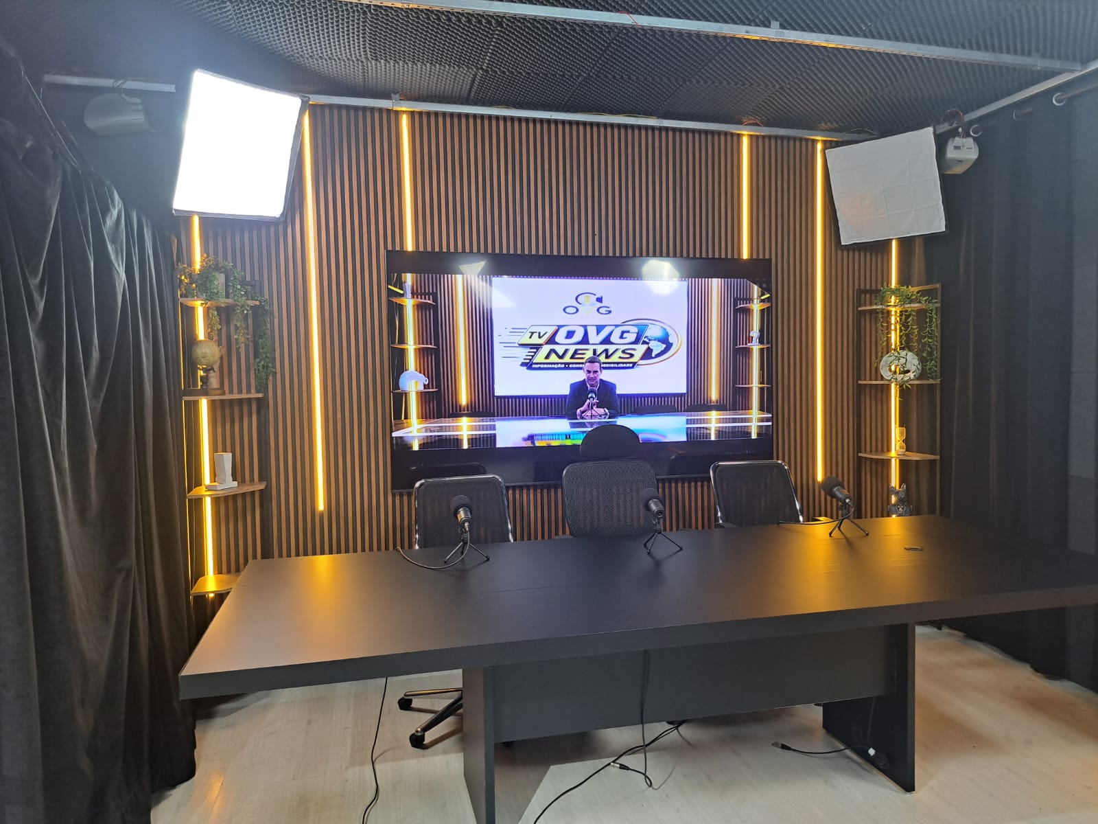 Interior do estúdio da OVG com set de podcast, microfones e telão exibindo a marca TV OVG